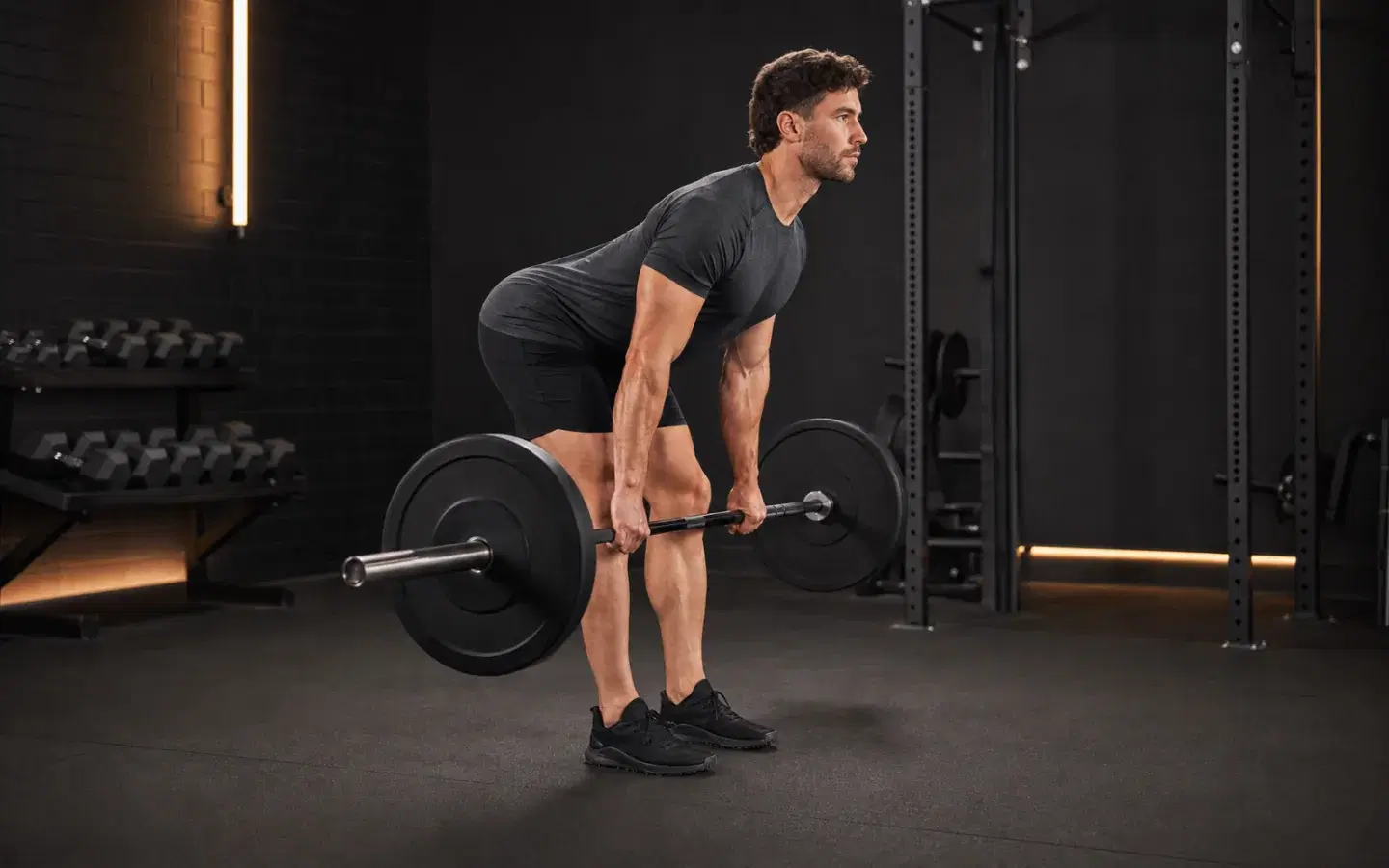 Athlete performing a barbell Romanian deadlift with a controlled hip hinge.