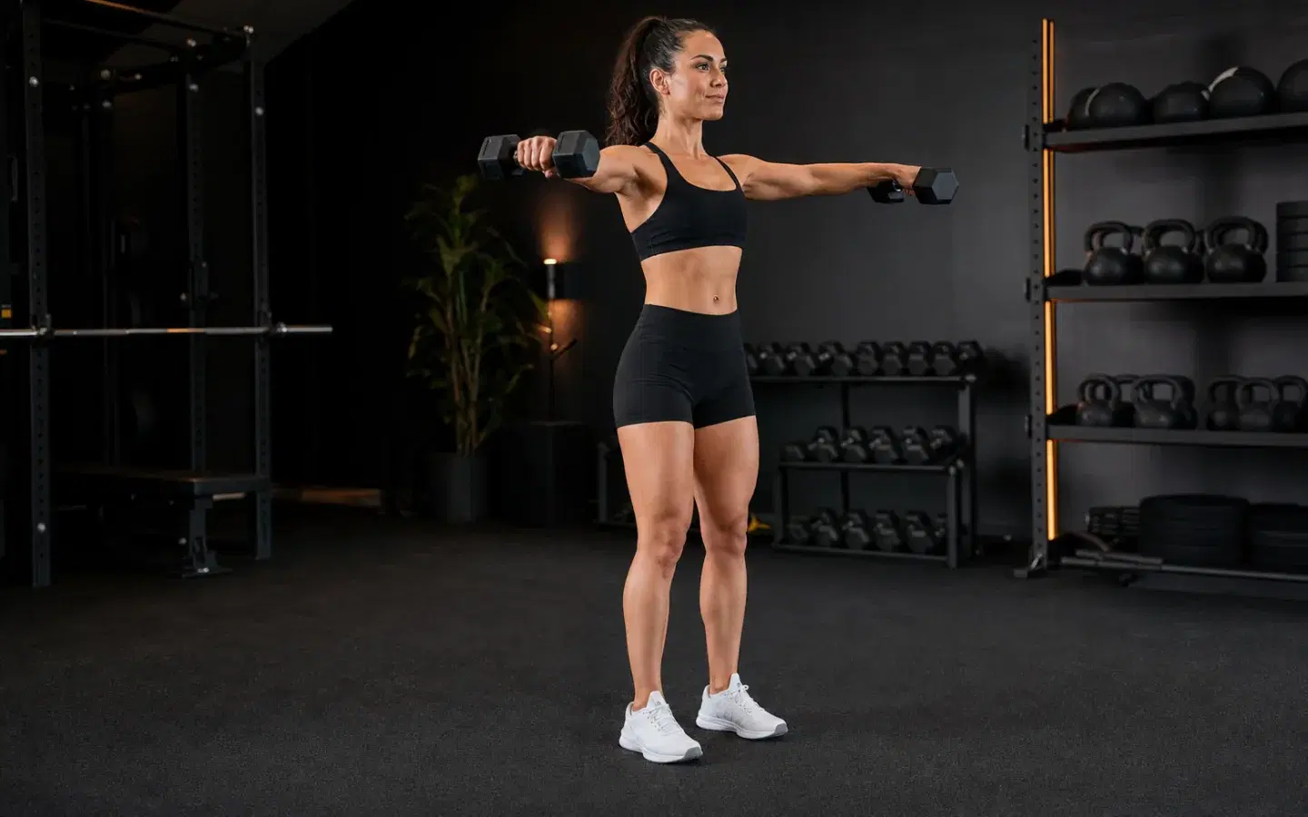 Athlete performing a controlled dumbbell lateral raise at shoulder height.